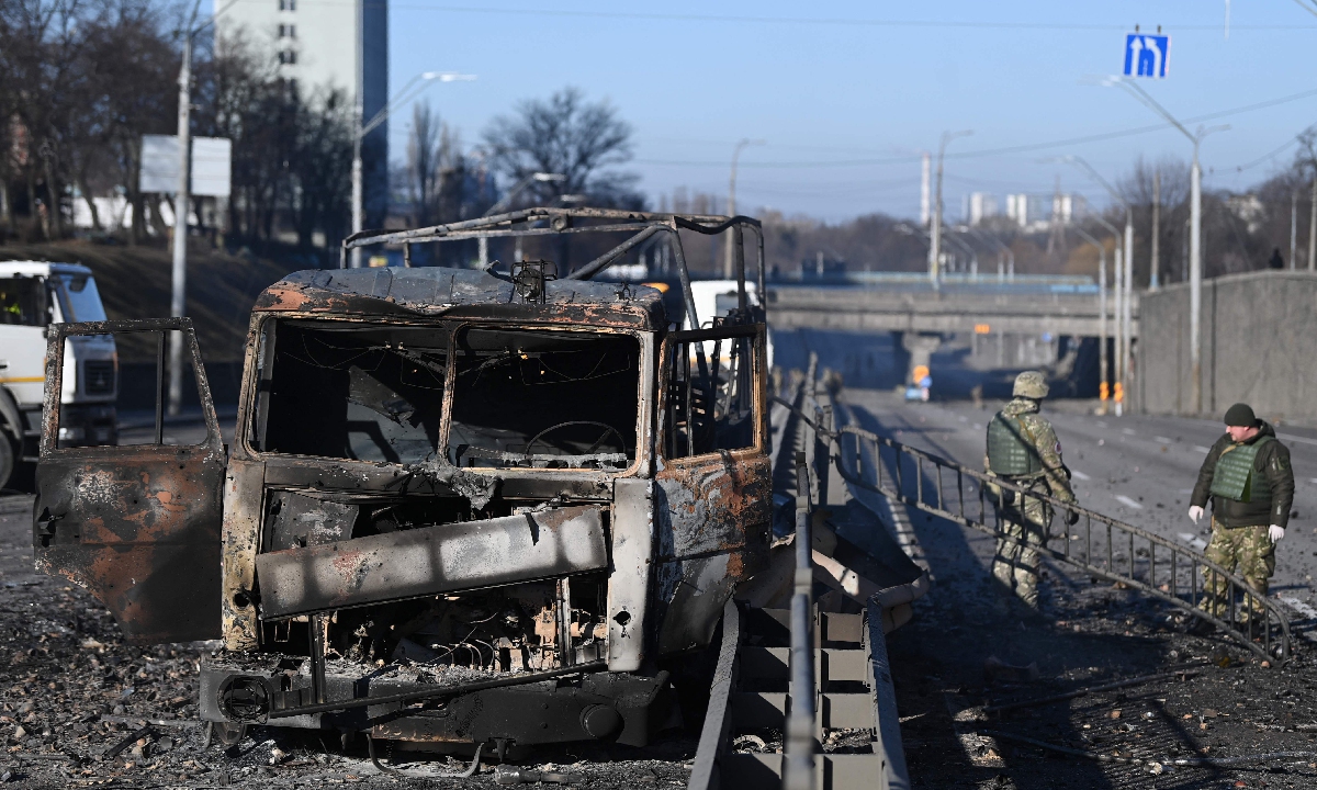 Ukrainian soldiers stand next to a burnt Ukrainian army vehicle on the west side of the capital Kyiv on February 26, 2022. Ukraine?and?Russia?are set to hold negotiations at the?Belarusian-Ukrainian border. Photo: AFP