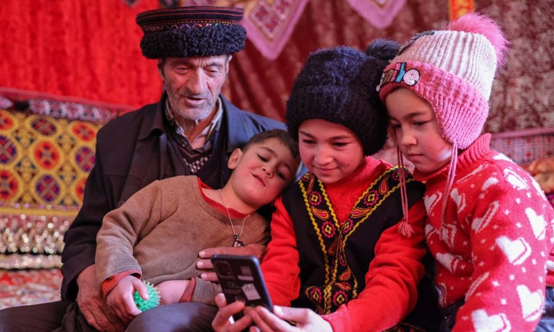 Children watch videos on a mobile phone with a family member in Rasekam Village of Taxkorgan Tajik Autonomous County, northwest China's Xinjiang Uygur Autonomous Region, Feb. 24, 2022.Photo:Xinhua