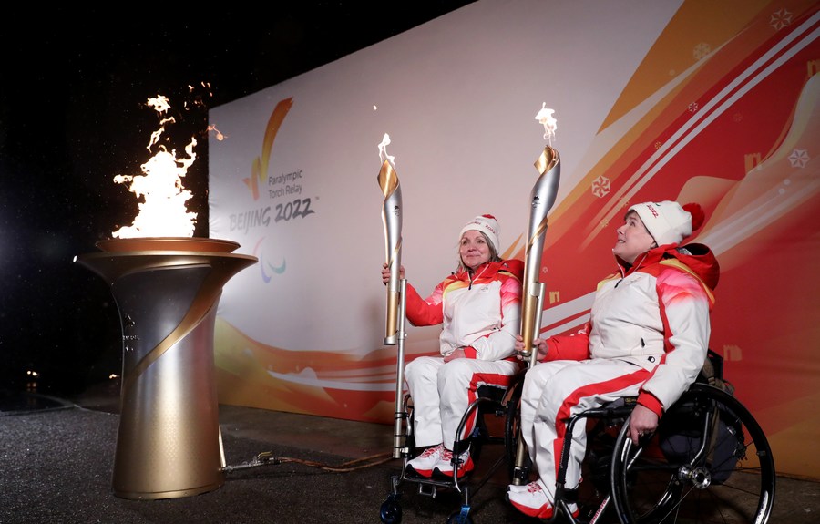 Torch bearers Aileen Neilson (R) and Angie Malone, wheelchair curlers, hold their torches during the Paralympic Heritage Flame Lighting Ceremony for the Beijing 2022 Winter Paralympic Games in Stoke Mandeville, Britain, Feb. 28, 2022. Photo: Xinhua/Li Ying