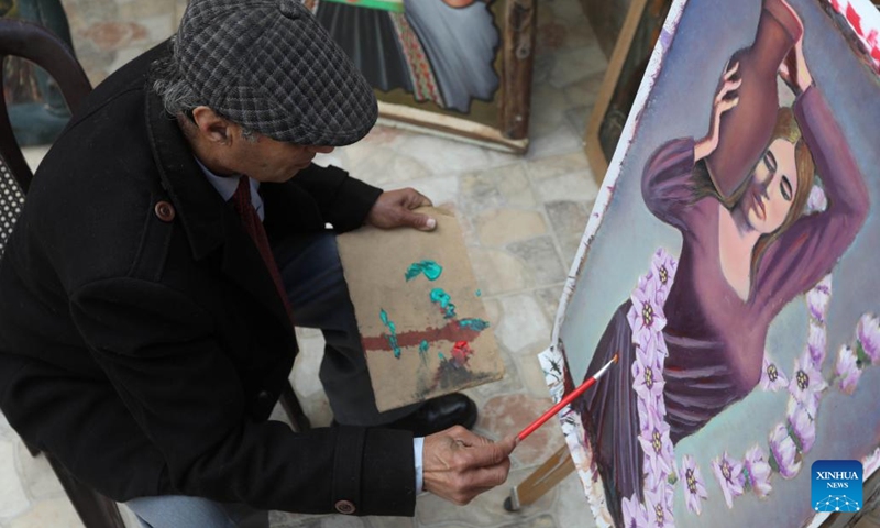 Murshid Gharib, a 73-year-old painter from Jenin who has about 50 years of experience in painting murals, works on a painting at his house in the West Bank city of Jenin, Feb. 21, 2022. TO GO WITH Feature: Palestine artists turn walls into canvas for hope(Photo: Xinhua)