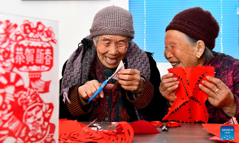 Two elderly women chat with each other while making paper-cuts at a care center for the elderly in Huangjiayu Village of Lanshan District, Rizhao, east China's Shandong Province, Feb. 27, 2022. Lanshan District of Rizhao City has set up care centers since 2021, providing assistance and care to the elderly people over 60 years old.(Photo: Xinhua)