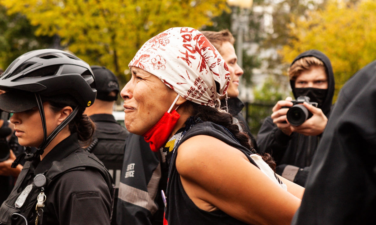 A Native American cries for the crimes against her people, and then in physical pain, as she is handled roughly by United States Secret Service when arrested on October 11, 2021.