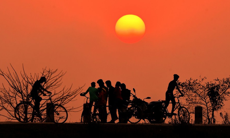 People are seen in silhouette during the sunset in Nagaon district of India's northeastern state of Assam, March 5, 2022.Photo:Xinhua
