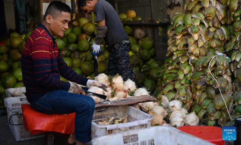 A vendor processes coconuts at a local market in Haikou, south China's Hainan Province, March 8, 2022.(Photo: Xinhua)