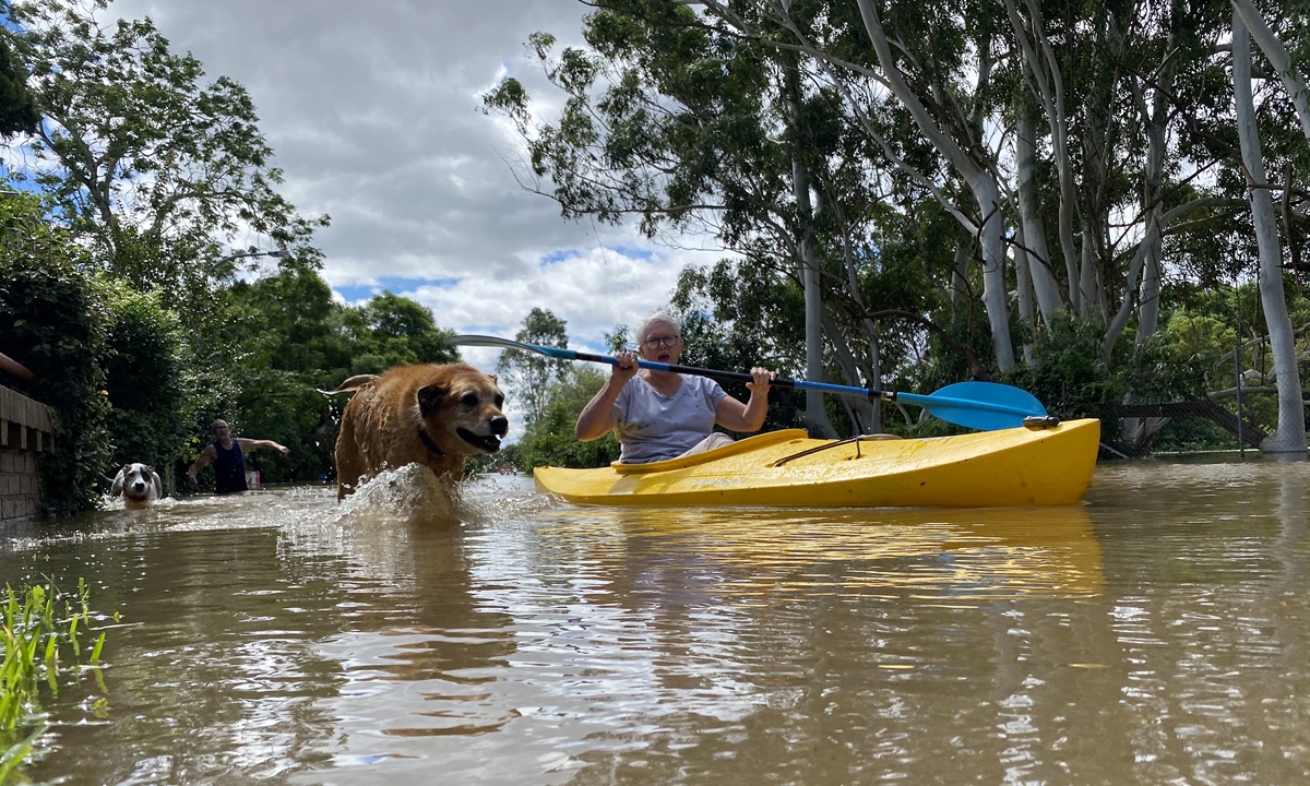 A woman kayaks with her dog to move around her flooded neighborhood in the Windsor suburb of Sydney, Australia on March 9, 2022. Photo: AFP