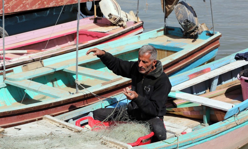 A fisherman preparing fishing nets while sitting in his boat in the Tigris River in Baghdad, Iraq, on March 4, 2022.(Photo: Xinhua)