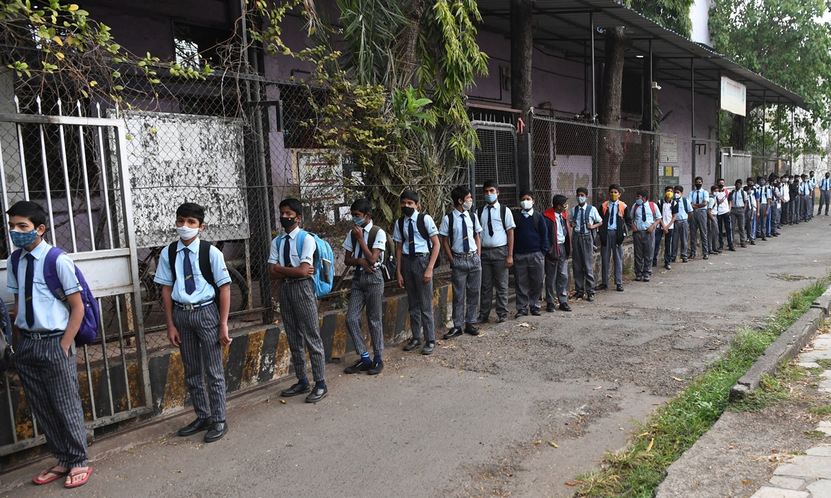 Students stand in a queue as they wait to enter their school in Mumbai, India on January 24, 2022, after schools were reopened that had been closed as a preventive measure to curb the spread of COVID-19. Photo: AFP