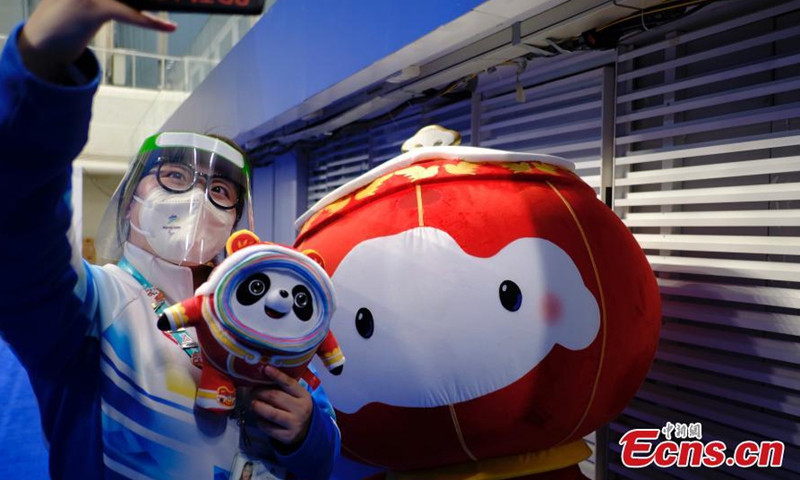 A volunteer takes photos with Shuey Rhon Rhon, the red lantern-shaped mascot of Beijing 2022 Winter Paralympic Games, appears at the National Aquatics Center, also known as the Ice Cube, venue of wheelchair curling competition of the Games in Beijing, March 10, 2022.Photo:China News Service