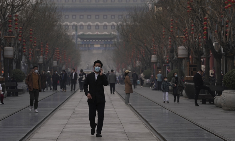 Residents walk in a street in Beijing, wearing face masks, on March 10, 2022. Photo: VCG
