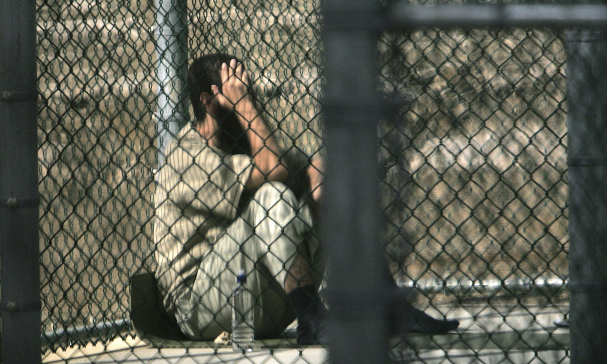 A detainee sits alone inside a fenced area during his daily outside period in Guantanamo Bay detention facility on December 5, 2006. Photo: VCG
