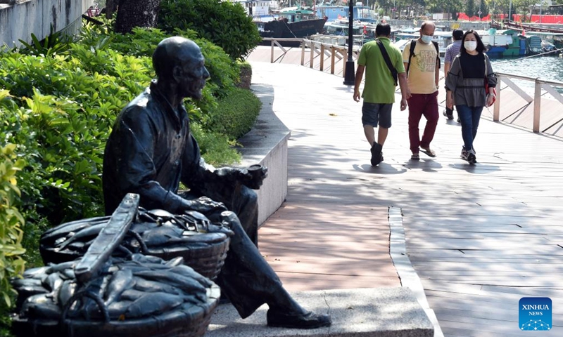 People wearing masks walk on a path in south China's Hong Kong, March 13, 2022. On Sunday, Hong Kong registered 13,335 new COVID-19 cases by nucleic acid tests, and 19,095 additional positive cases through self-reported rapid antigen tests, official data showed.Photo:Xinhua