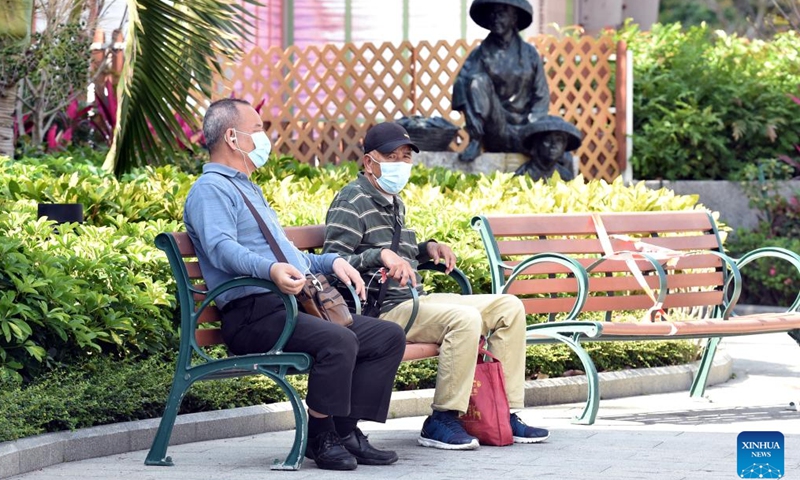 People wearing masks sit on a bench in south China's Hong Kong, March 13, 2022.Photo:Xinhua