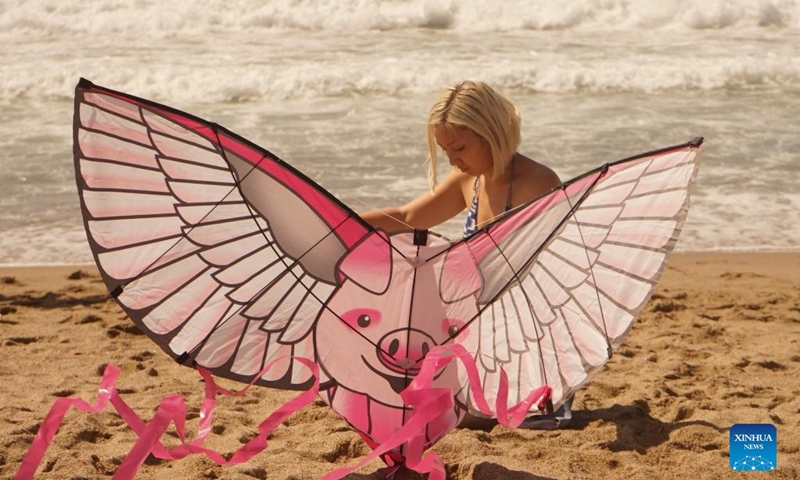 A woman prepares to fly a kite at the Redondo Beach in Los Angeles, California, the United States on March 13, 2022. Thousands of people on Sunday gathered at the Redondo Beach Pier in Los Angeles for its 48th Annual Festival of the Kite. (Photo by Zeng Hui/Xinhua)