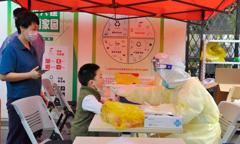 A medical worker takes a swab sample from a child for nucleic acid test at a community in east China's Shanghai, March 13, 2022.Photo:Xinhua