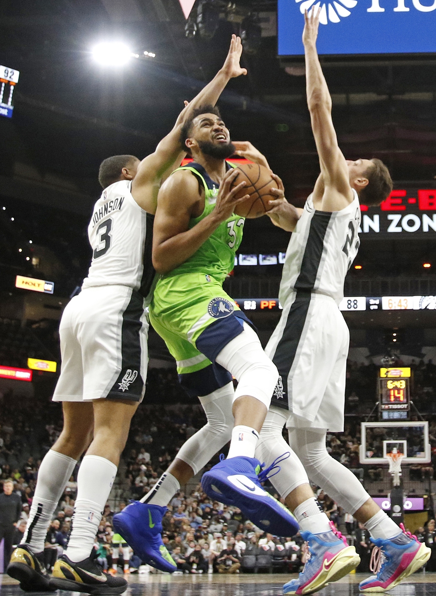 Karl-Anthony Towns (center) of the Minnesota Timberwolves drives over Keldon Johnson of the San Antonio Spurs on March 14, 2022 in San Antonio, Texas. Photo: VCG