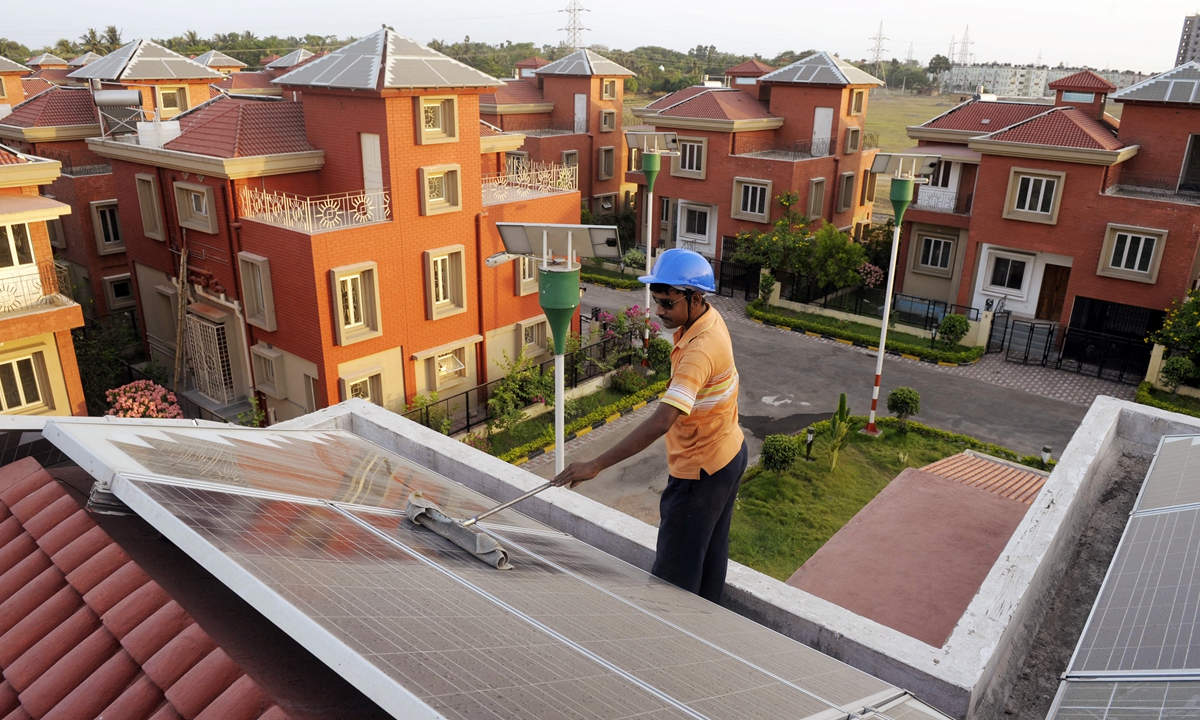 An Indian worker cleans solar panels fitted onto the roof of a residential house in Rabirashmi Abasan, a solar housing complex at Rajarhat, India on April 20, 2010. Photo: AFP