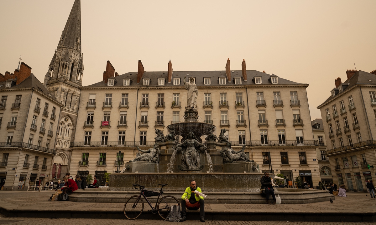 Residents sit on the Place Royale under a yellow ochre sky caused by Saharan dust in Nantes, western France, on March 15, 2022. Photo: AFP 