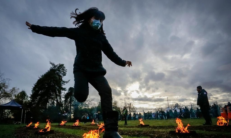 A girl leaps over a bonfire during the Fire Festival at Ambleside Park in West Vancouver, British Columbia, Canada, March 15, 2022. Fire Festival is celebrated by Iranians on the eve of the last Wednesday before Nowruz, the Iranian new year. (Photo by Liang Sen/Xinhua)