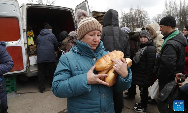 A local resident carries received bread in Volnovakha of Donetsk, March 15, 2022. (Photo by Victor/Xinhua)