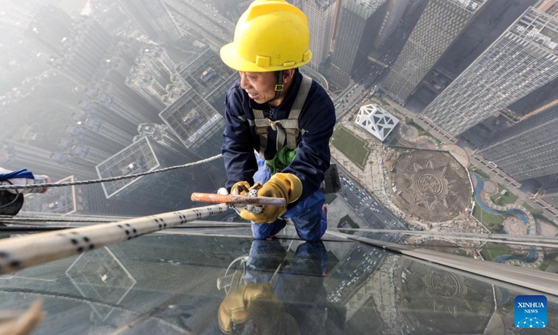 A skyscraper window cleaner cleans the exterior of Guiyang International Trade Center in Guiyang, southwest China's Guizhou Province, March 15, 2022. The 335-meter-high twin skyscrapers of Guiyang International Trade Center recently saw their first exterior wall cleaning this year. The cleaning, carried out by eight workers, is expected to take about 20 days.(Photo: Xinhua)