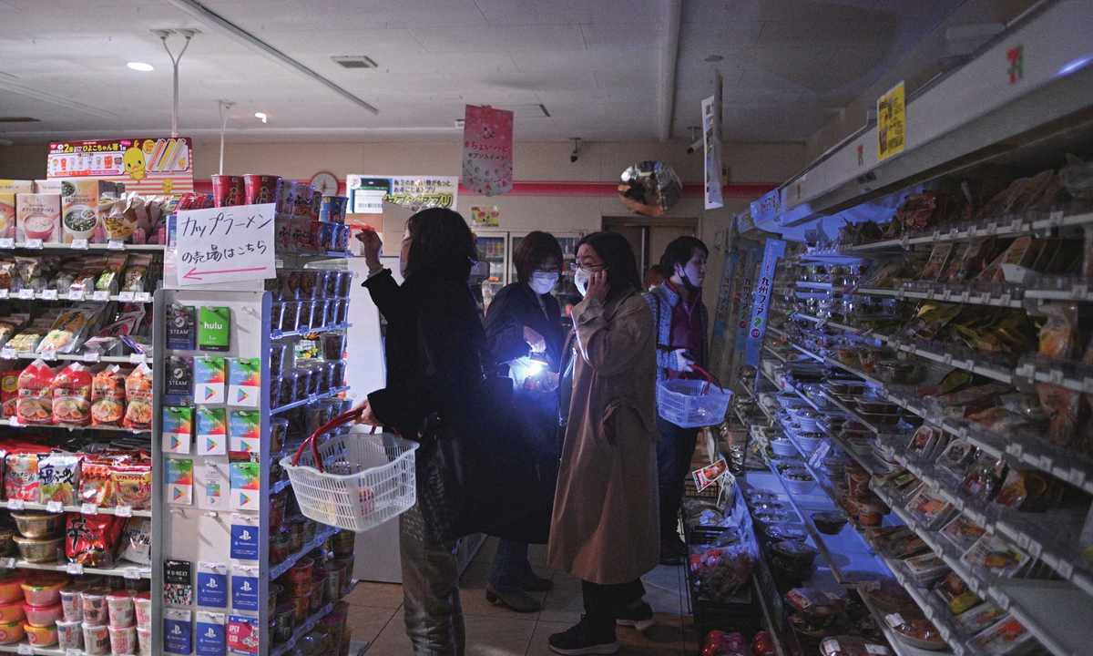 People shop at a store in a residential area during a power outage in Koto district in Tokyo on March 16, 2022, after a powerful 7.3-magnitude quake jolted east Japan. Nikkei reported that no abnormalities were detected at the Fukushima Daini nuclear plant, according to regulators. NHK reported about 2 million households were without power. Photo: AFP
