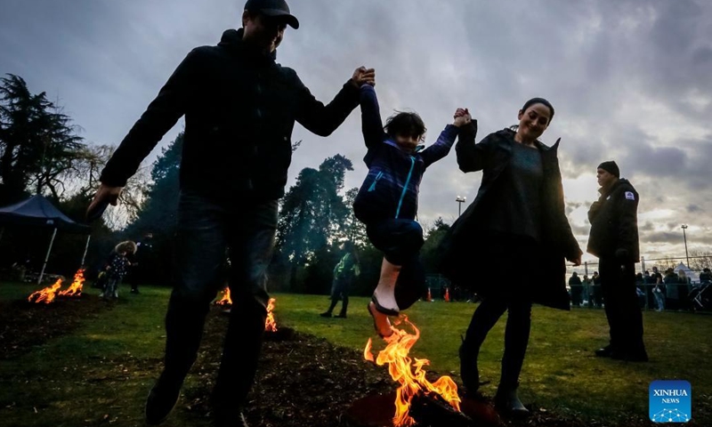 People leap over a bonfire during the Fire Festival at Ambleside Park in West Vancouver, British Columbia, Canada, March 15, 2022. Fire Festival is celebrated by Iranians on the eve of the last Wednesday before Nowruz, the Iranian new year. (Photo by Liang Sen/Xinhua)
