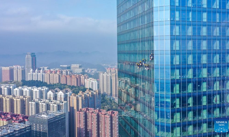 Aerial photo taken on March 15, 2022 shows skyscraper window cleaners cleaning the exterior of Guiyang International Trade Center in Guiyang, southwest China's Guizhou Province. The 335-meter-high twin skyscrapers of Guiyang International Trade Center recently saw their first exterior wall cleaning this year. The cleaning, carried out by eight workers, is expected to take about 20 days. (Photo: Xinhua)