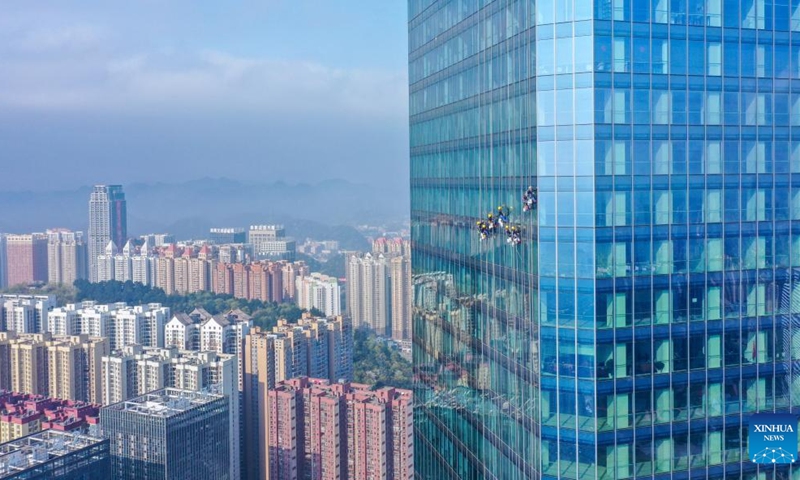 Aerial photo taken on March 15, 2022 shows skyscraper window cleaners cleaning the exterior of Guiyang International Trade Center in Guiyang, southwest China's Guizhou Province. The 335-meter-high twin skyscrapers of Guiyang International Trade Center recently saw their first exterior wall cleaning this year. The cleaning, carried out by eight workers, is expected to take about 20 days. (Photo: Xinhua)