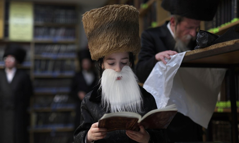 An ultra-Orthodox child wearing costume for Purim reads the Megillat Esther during the Jewish holiday of Purim at a synagogue in Ashdod, southern Israel, on March 16, 2022.(Photo: Xinhua)