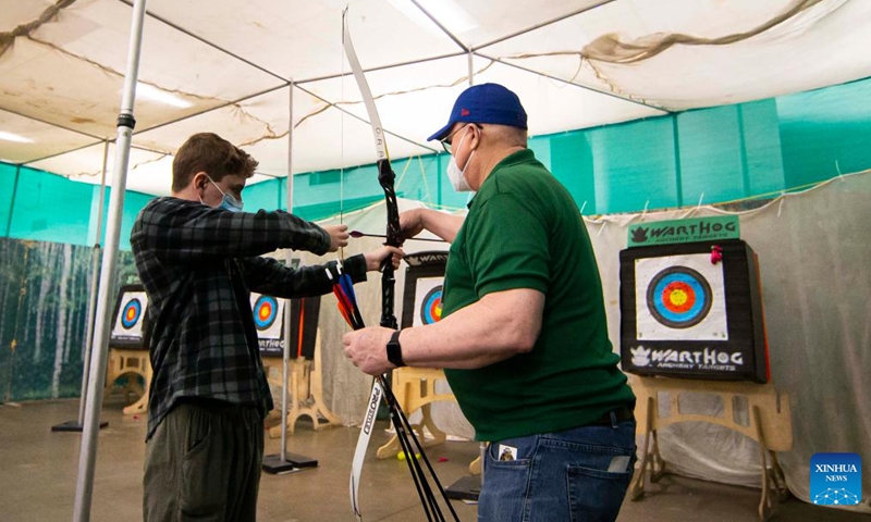 A boy learns archery from a coach during the 2022 Toronto Sportsmen's Show in Mississauga, the Greater Toronto Area, Canada, on March 17, 2022. As the biggest event for outdoor enthusiasts in Ontario, the 2022 Toronto Sportsmen's Show is held here from March 17 to 20.(Photo: Xinhua)