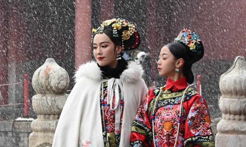 People pose for pictures amid snow at the Palace Museum in Beijing, capital of China, March 18, 2022.Photo:Xinhua