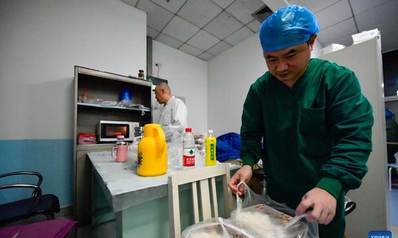Staff members heat food during work shift at the lounge of a nucleic testing base in Hebei District of Tianjin, north China, March 19, 2022. Photo:Xinhua 