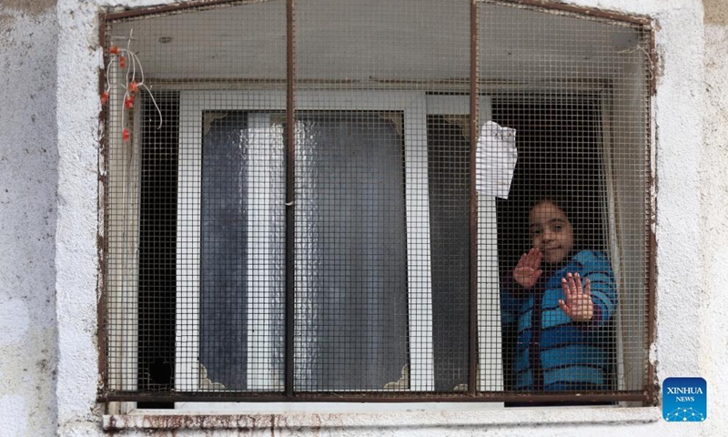 A Palestinian refugee girl looks out from her house window at Balata refugee camp in the West Bank city of Nablus, March 16, 2022.Photo:Xinhua