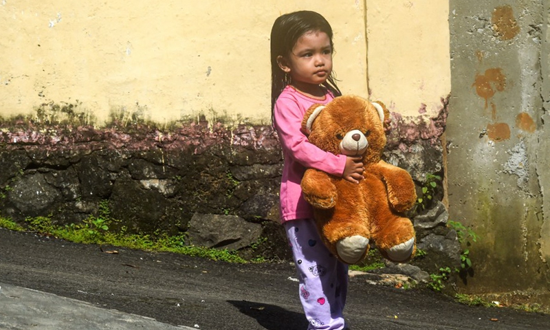 A girl holds a teddy bear on her way to a storytelling event for children on World Storytelling Day in Kampong Dongeng community in Indonesia's Banten Province on March 20, 2022.Photo:Xinhua