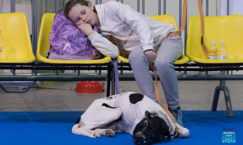 A girl from Ukraine takes a rest with her dog at a new transit shelter opened by the Defense Committee of Budapest at the Budapest Olympic Center in Budapest, Hungary on March 21, 2022. (Photo by Attila Volgyi/Xinhua)
