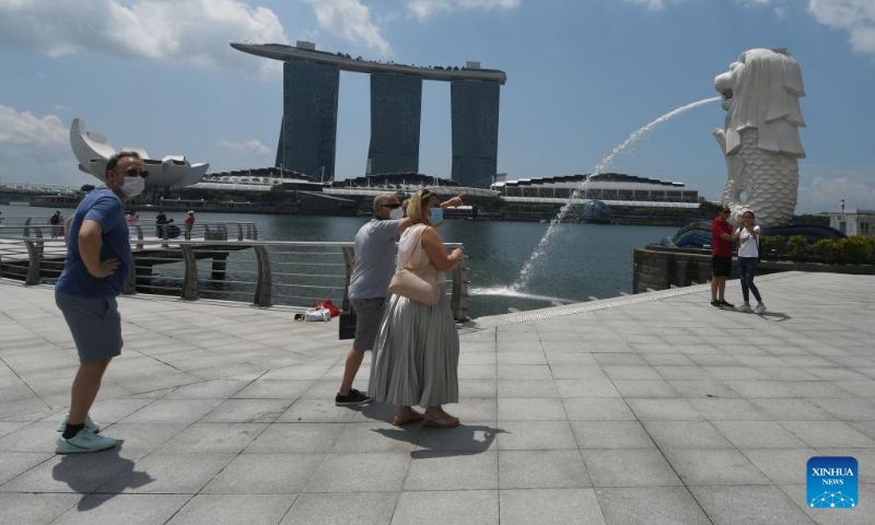 Tourists wearing face masks visit the Merlion Park in Singapore on March 24, 2022. Singapore will further relax its COVID-19 restrictions as the number of infected cases has declined, Prime Minister Lee Hsien Loong said on Thursday. (Photo by Then Chih Wey/Xinhua)