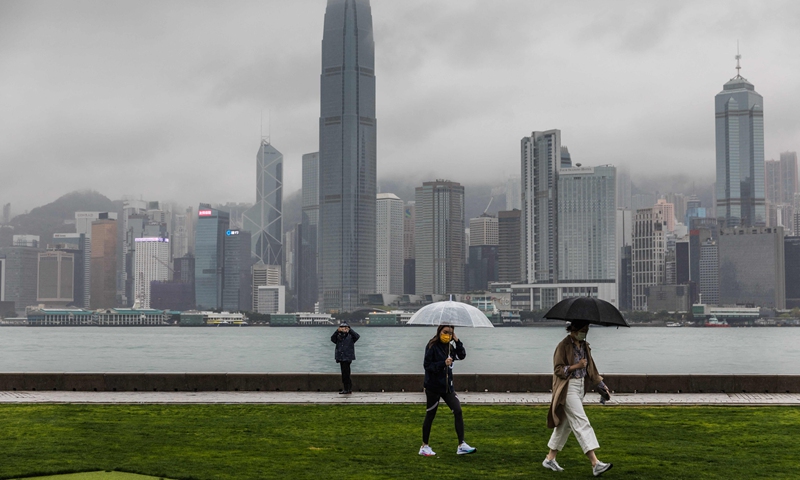 People walk along a waterfront next to Victoria Harbour as it rains in Hong Kong on March 23, 2022. Photo: VCG
