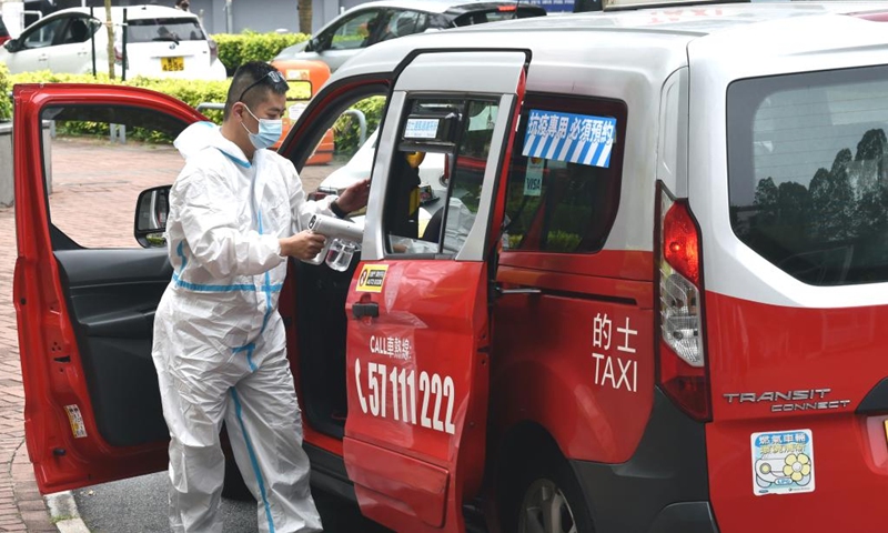 A driver disinfects a taxi designated for epidemic control in Hong Kong, south China, March 22, 2022. (Photo: Xinhua)