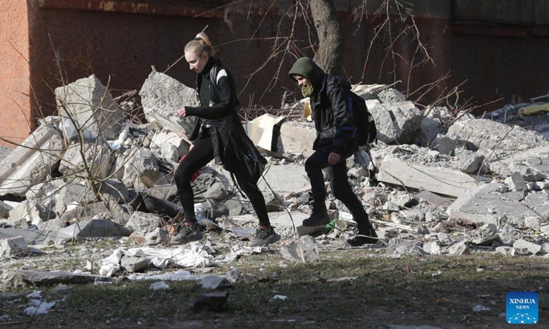 People pass by a damaged building in Mariupol, Ukraine, March 23, 2022.(Photo: Xinhua)