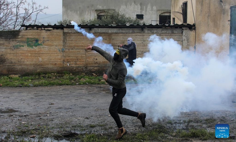 A Palestinian protester throws back a tear gas canister fired by Israeli soldiers during clashes after a protest against the expansion of Jewish settlements in Kufr Qadoom village near the West Bank city of Nablus, March 25, 2022.(Photo: Xinhua)