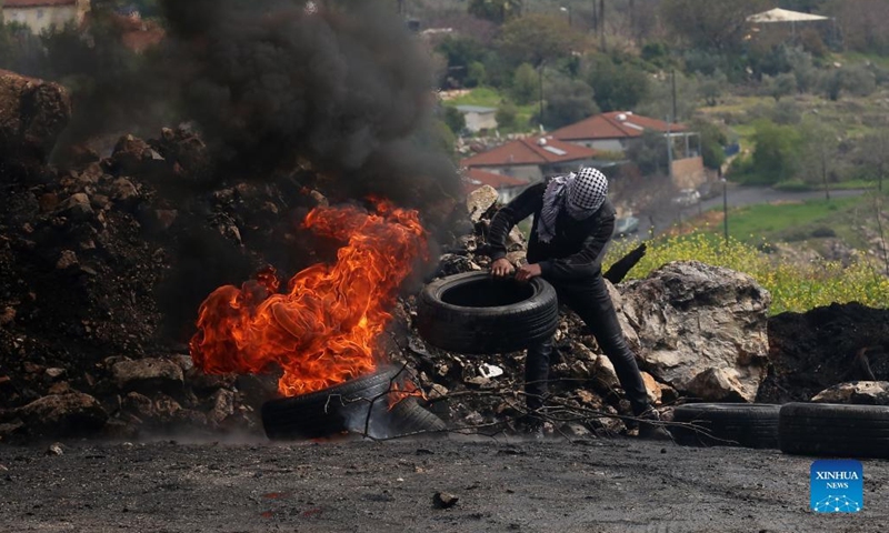 A Palestinian protester burns tires during clashes with Israeli soldiers after a protest against the expansion of Jewish settlements in Kufr Qadoom village near the West Bank city of Nablus, March 25, 2022.(Photo: Xinhua)