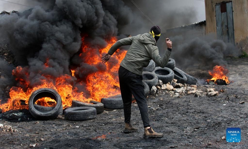 A Palestinian protester uses a slingshot to hurl a stone at Israeli soldiers during clashes after a protest against the expansion of Jewish settlements in Kufr Qadoom village near the West Bank city of Nablus, March 25, 2022.(Photo: Xinhua)