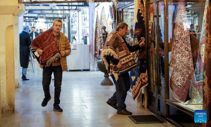 People carry Turkish carpets in the Grand Bazaar in Istanbul, Turkey, April 5, 2022. (Photo by Unal Cam/Xinhua)