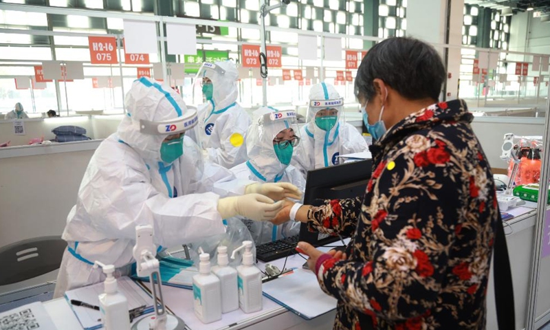 Staff members help a patient to register at a designated quarantine facility in east China's Shanghai, March 26, 2022.Photo:Xinhua