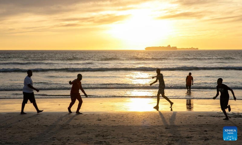 People have fun on Sunset Beach at sunset in Cape Town, South Africa, on March 26, 2022.Photo:Xinhua
