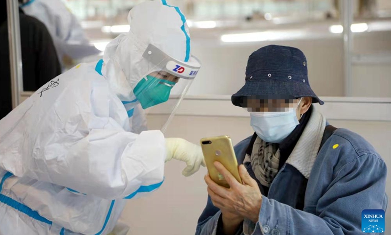 A staff member helps a patient to register at a designated quarantine facility in east China's Shanghai, March 26, 2022.Photo:Xinhua
