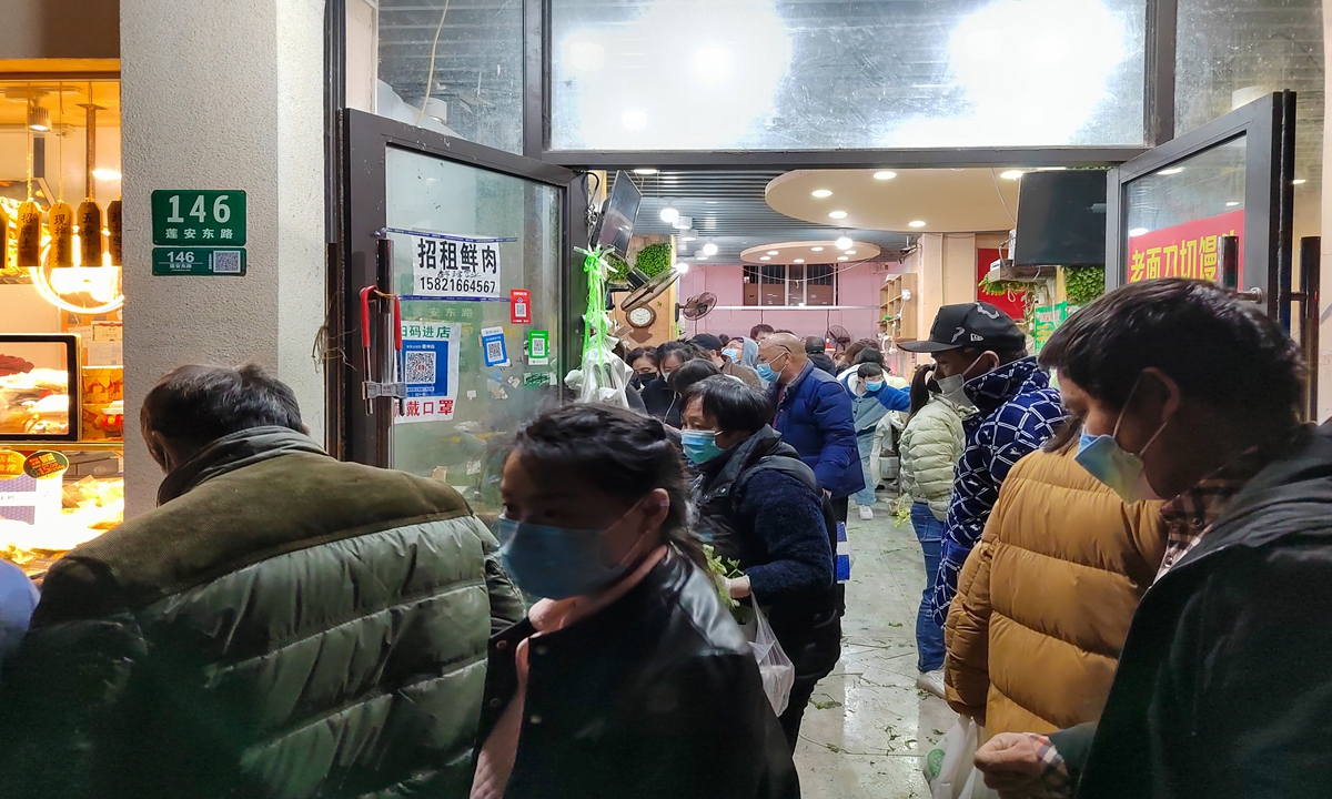 Shanghai residents line up to purchase daily commodities in Pudong on Sunday night, which will be put under closed-loop management from Monday to Friday. Photo: VCG