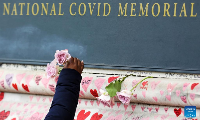 A woman puts a flower on the National COVID Memorial Wall in London, Britain, March 27, 2022. (Photo: Xinhua)