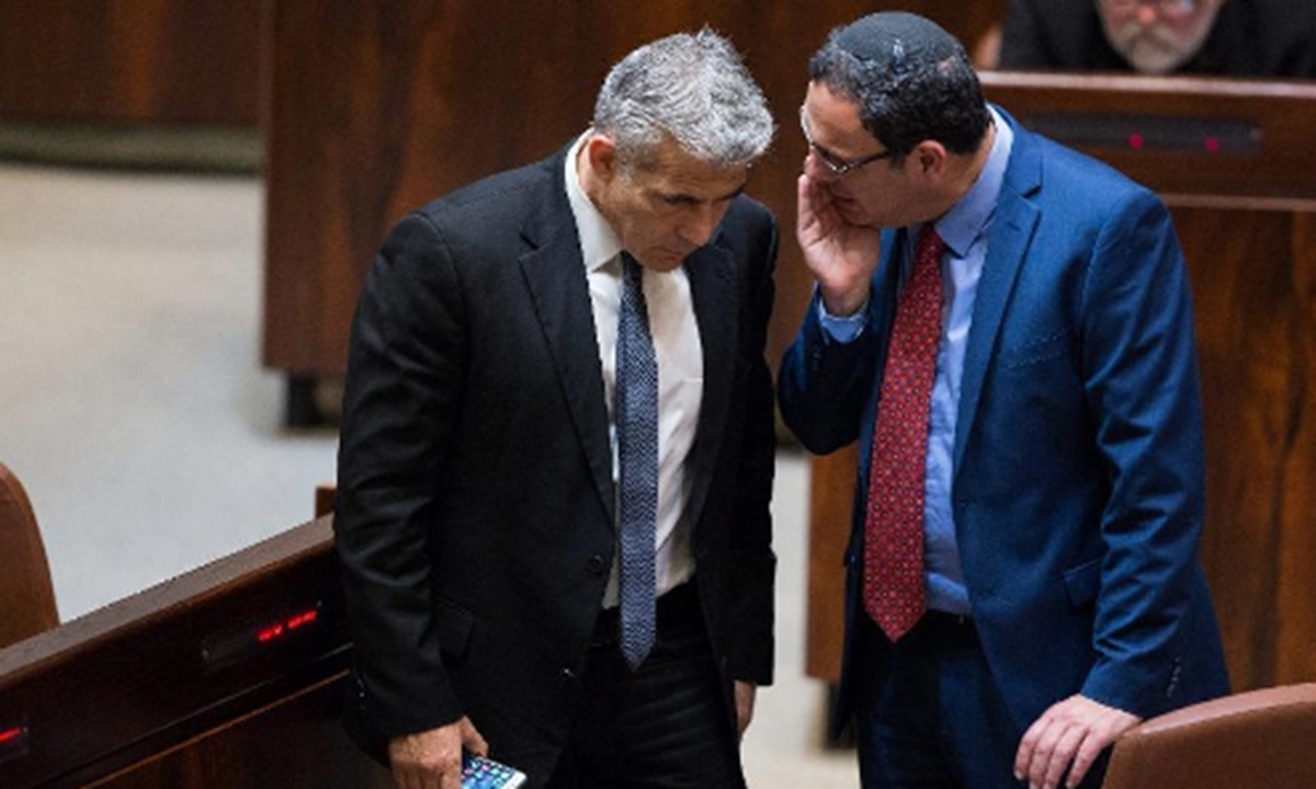Former Israeli Finance Minister Yair Lapid (L) speaks with former Minister of Education Shay Piron during a vote on a bill to dissolve the Knesset (parliament) at the Knesset in Jerusalem, on Dec. 8, 2014. (Xinhua/JINI)  
