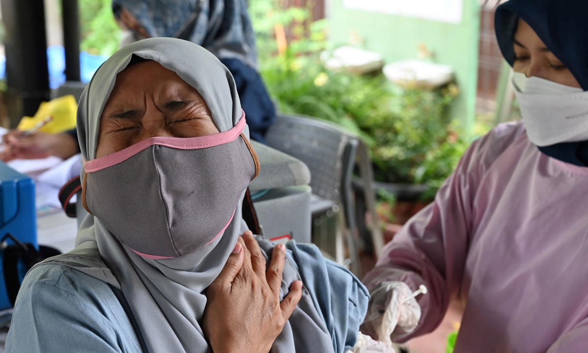 A woman (left) reacts while receiving a Pfizer booster vaccine for COVID-19 in Jakarta, Indonesia on March 29, 2022. The government has accelerated vaccination programs ahead of Eid al-Fitr in May, when many people leave the capital and return back to their hometowns. Photo: AFP